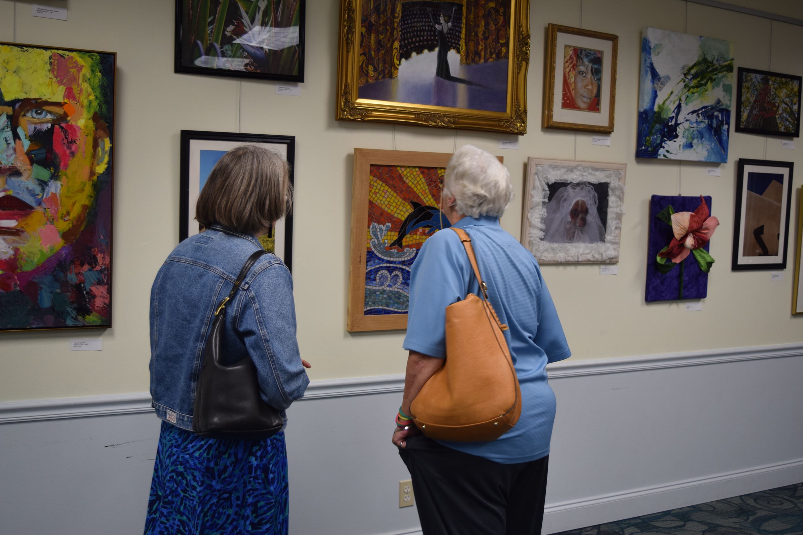 Two women looking at artwork on wall of gallery at Art Show
